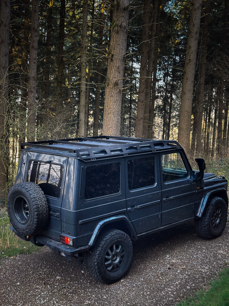 Dark G-Class rear view with Walger Works roof rack in forest